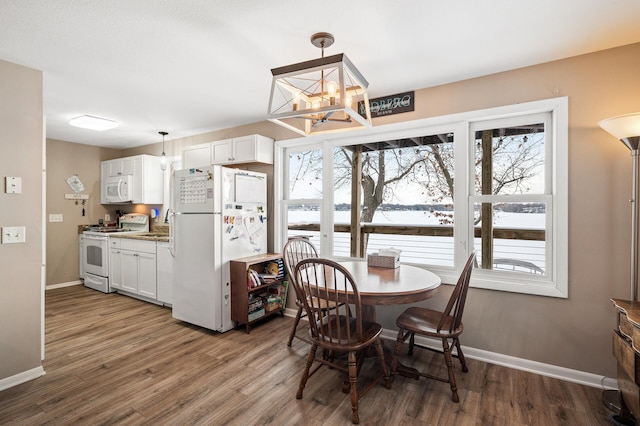 dining room with a healthy amount of sunlight, a notable chandelier, and dark hardwood / wood-style floors