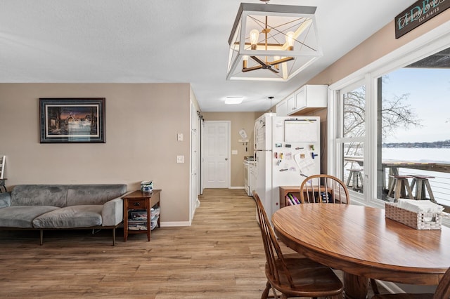 dining room featuring a barn door, a water view, a chandelier, and light wood-type flooring