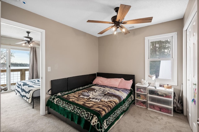 bedroom featuring a textured ceiling, ceiling fan, a closet, and light colored carpet