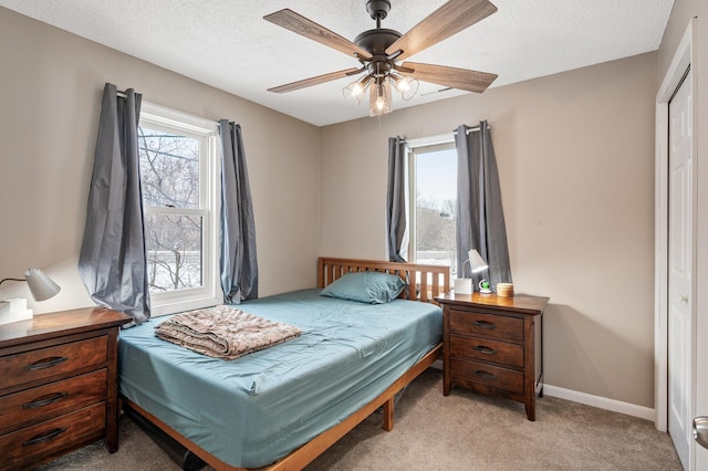 bedroom featuring ceiling fan, light carpet, and a textured ceiling