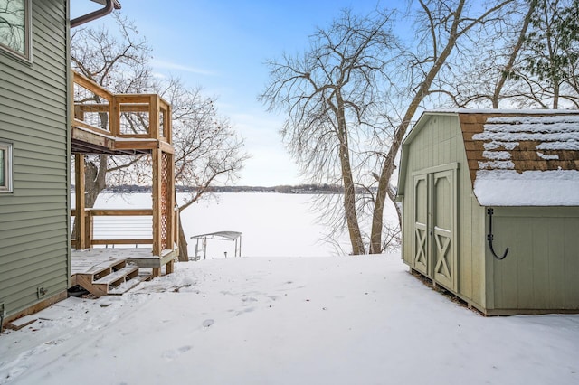 yard layered in snow featuring a shed