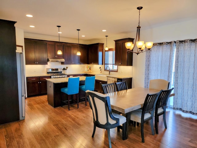 dining space with sink, light hardwood / wood-style flooring, and a notable chandelier