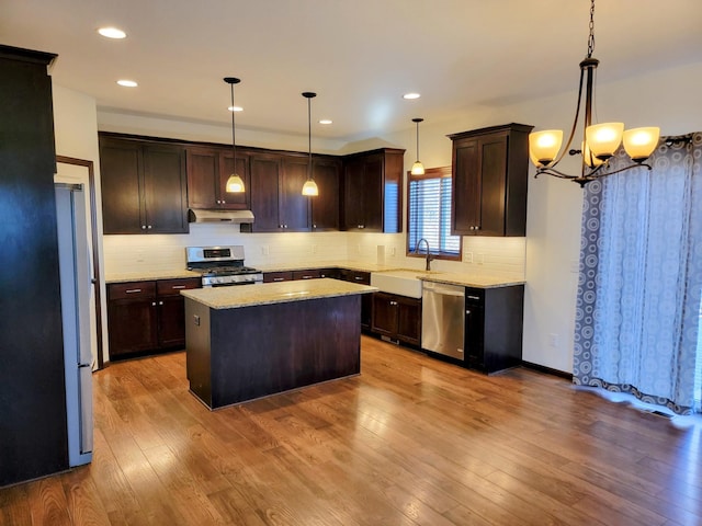 kitchen with hanging light fixtures, appliances with stainless steel finishes, dark brown cabinets, and a kitchen island