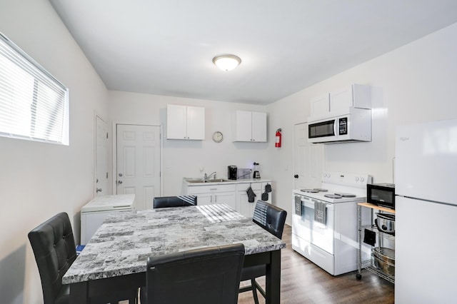 kitchen with white appliances, a center island, a breakfast bar area, and white cabinets