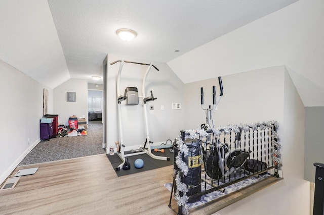 exercise area with wood-type flooring and vaulted ceiling