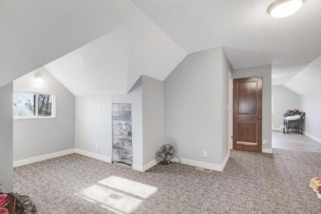 additional living space with light carpet, lofted ceiling, and a textured ceiling