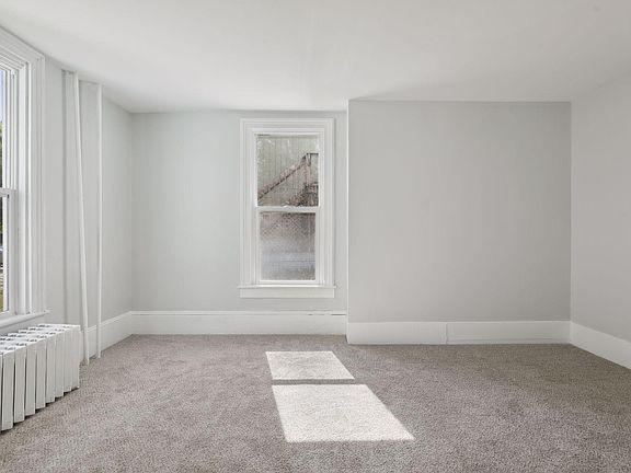 unfurnished room featuring light colored carpet and radiator