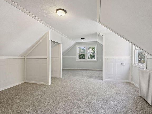 bonus room with a textured ceiling, vaulted ceiling, light carpet, and radiator