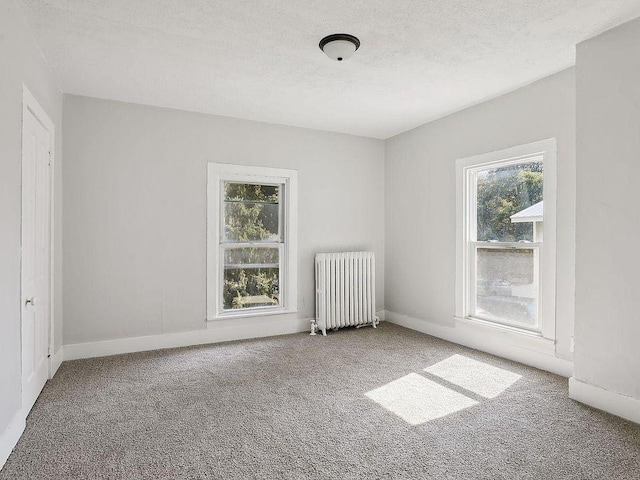 carpeted spare room with a textured ceiling and radiator