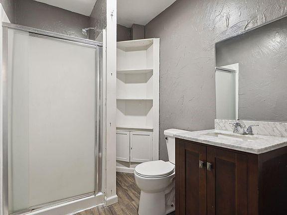 bathroom with toilet, hardwood / wood-style flooring, a shower with door, built in features, and vanity