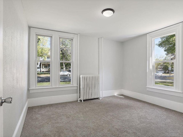 unfurnished room featuring radiator heating unit and carpet