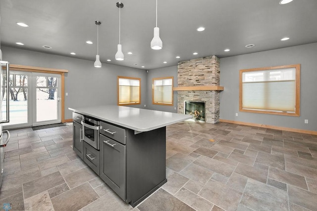 kitchen with decorative light fixtures, a stone fireplace, stainless steel oven, and a kitchen island