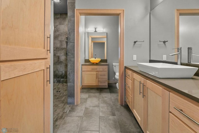 bathroom with vanity, toilet, and a tile shower