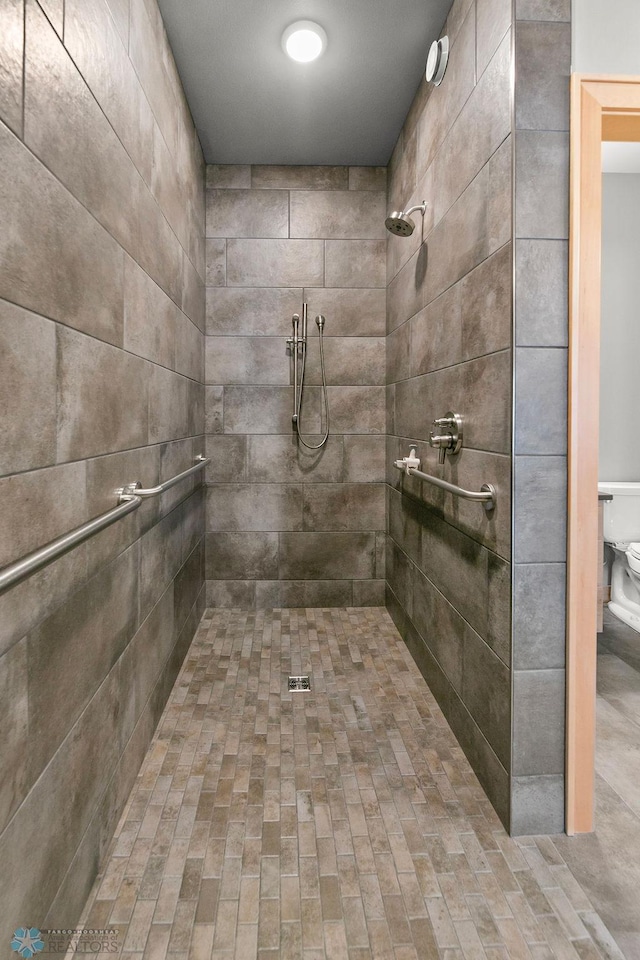 bathroom featuring a tile shower and toilet