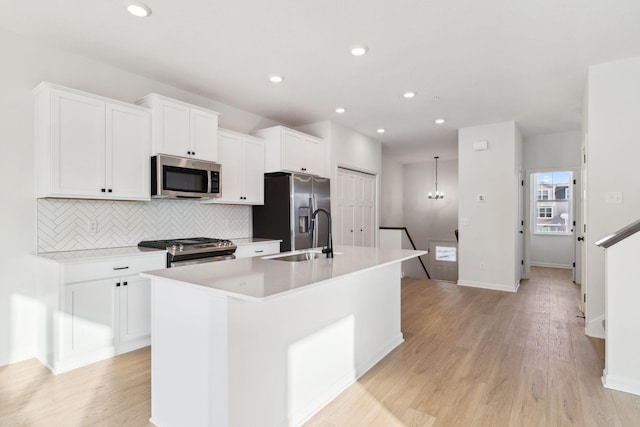 kitchen with white cabinetry, sink, a kitchen island with sink, stainless steel appliances, and light hardwood / wood-style flooring