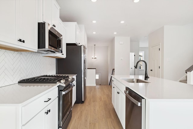 kitchen featuring white cabinetry, stainless steel appliances, sink, and a center island with sink