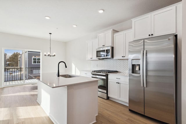 kitchen with pendant lighting, sink, stainless steel appliances, and white cabinets