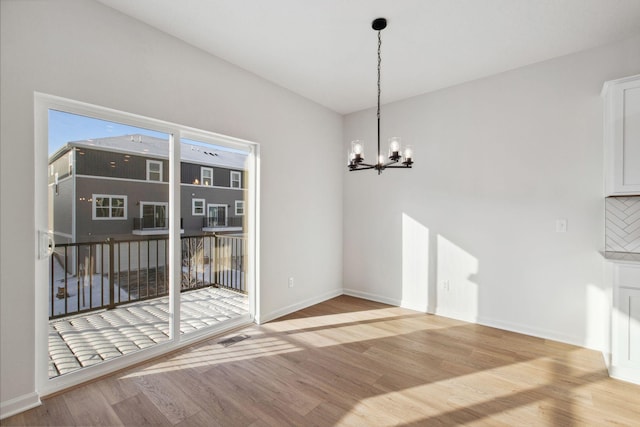 unfurnished dining area with an inviting chandelier and light hardwood / wood-style floors