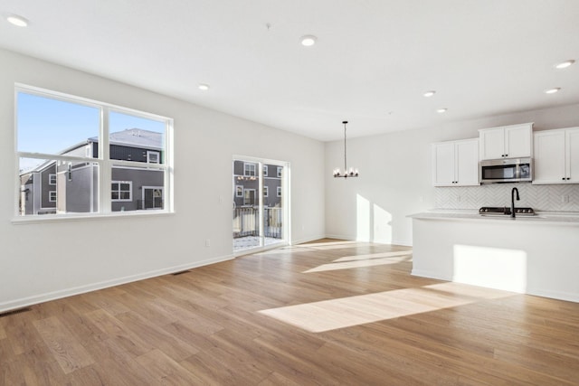 kitchen featuring white cabinetry, decorative light fixtures, light hardwood / wood-style flooring, a wealth of natural light, and decorative backsplash