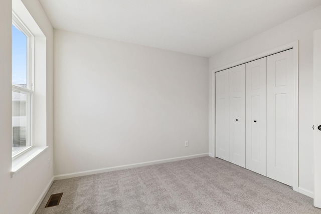 unfurnished bedroom featuring a closet and light carpet