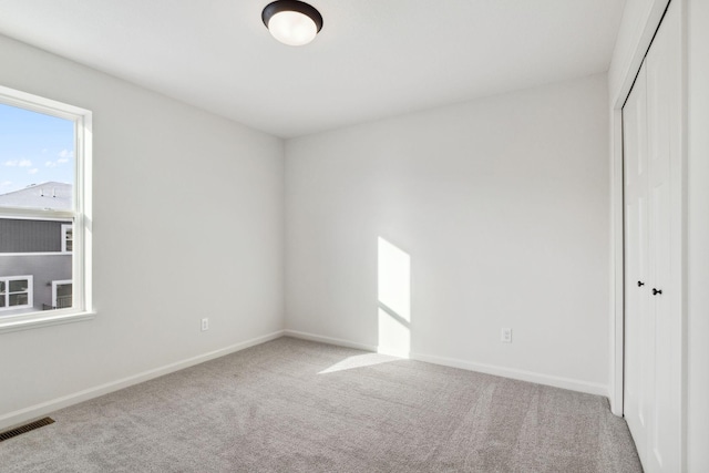 unfurnished bedroom featuring light carpet and a closet