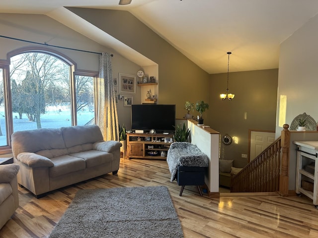 living room with light wood-type flooring, vaulted ceiling, and a notable chandelier