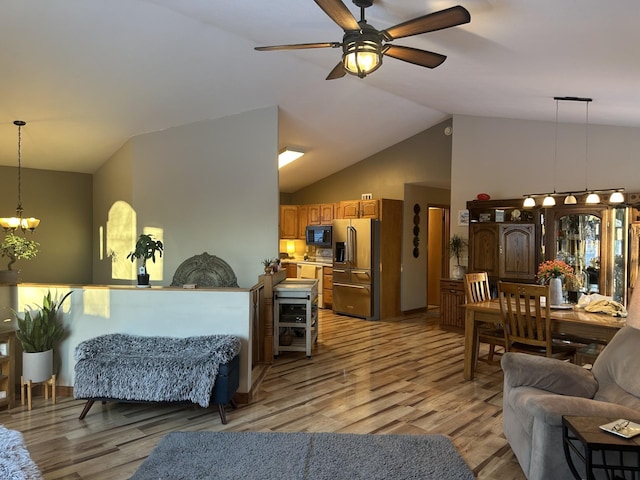 living room with ceiling fan with notable chandelier, high vaulted ceiling, and light wood-type flooring