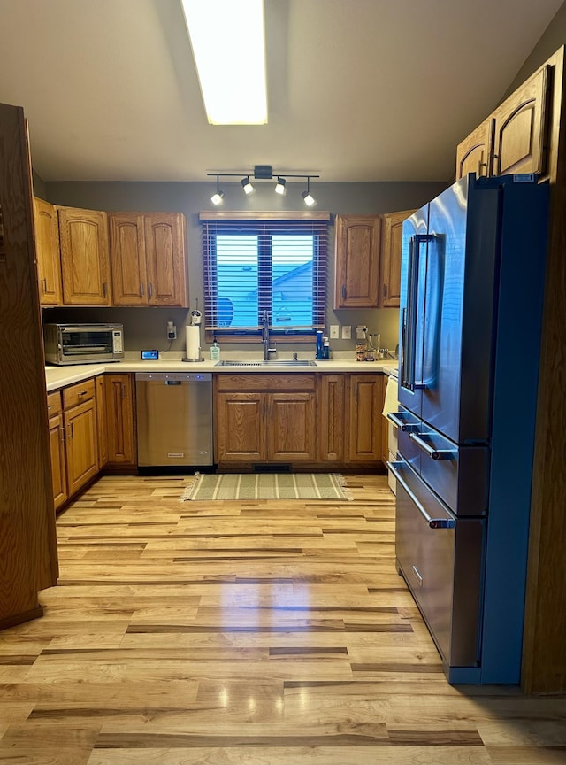 kitchen with sink, appliances with stainless steel finishes, and light hardwood / wood-style flooring