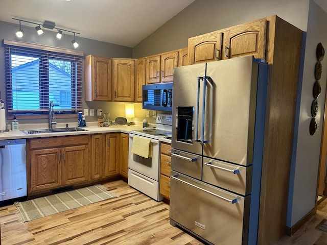 kitchen with vaulted ceiling, appliances with stainless steel finishes, light hardwood / wood-style flooring, and sink