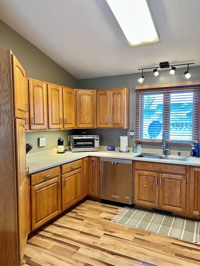 kitchen with lofted ceiling, dishwasher, sink, and light wood-type flooring