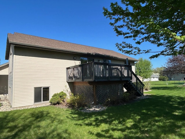 rear view of house featuring a yard, a deck, stairs, and a shingled roof