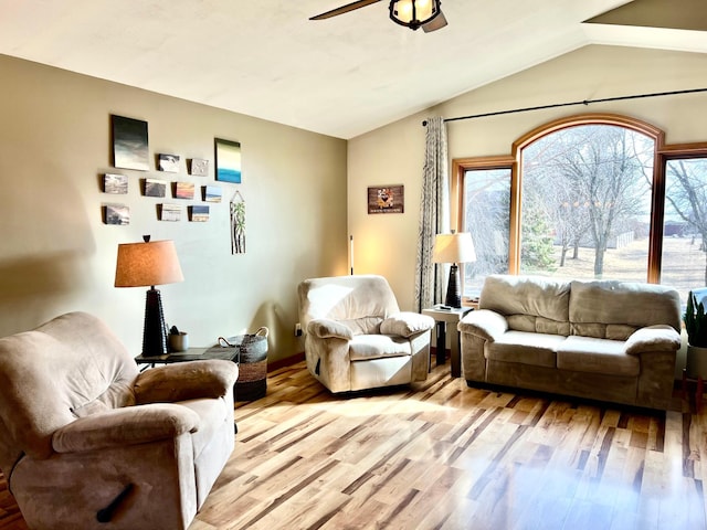 living room with a ceiling fan, light wood-type flooring, vaulted ceiling, and baseboards