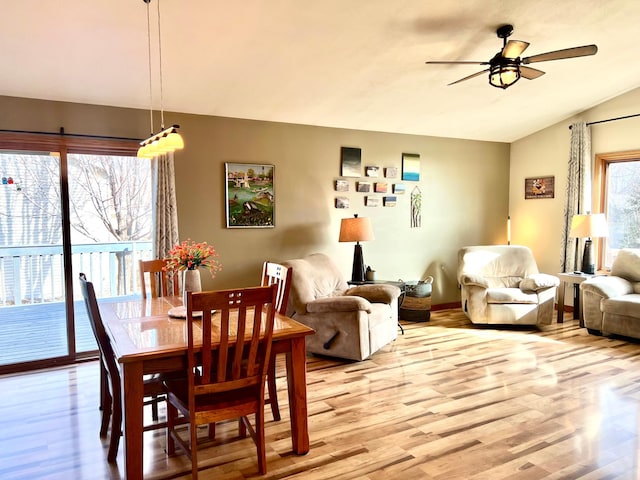 dining room with ceiling fan, light wood finished floors, and vaulted ceiling