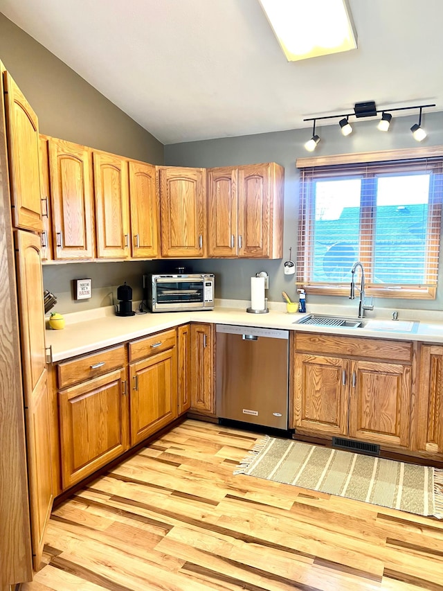 kitchen featuring dishwasher, a sink, light wood-style flooring, light countertops, and lofted ceiling