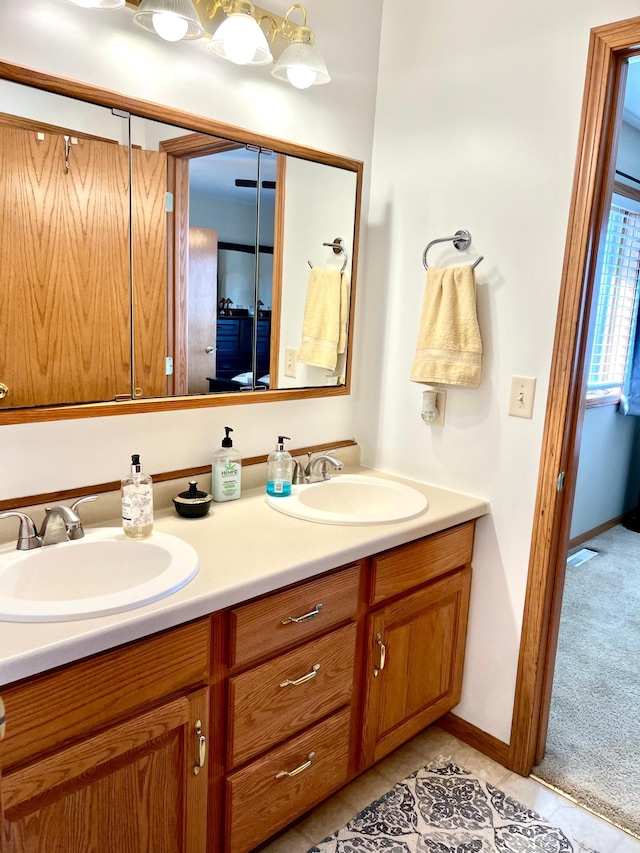 full bath featuring double vanity, tile patterned flooring, and baseboards