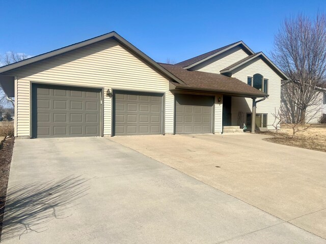 ranch-style home with concrete driveway, a garage, and a shingled roof