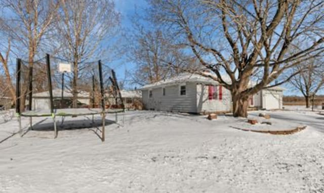 yard layered in snow featuring a storage shed and a trampoline