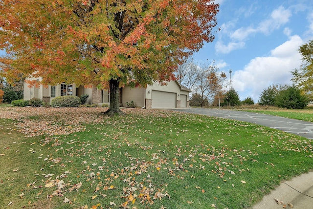 view of property hidden behind natural elements featuring a front yard and a garage