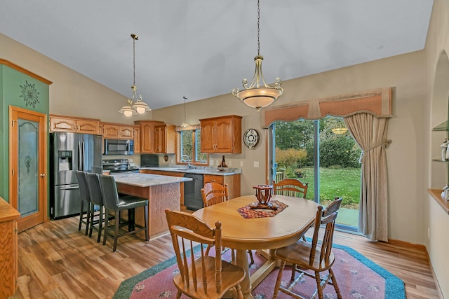 dining space featuring lofted ceiling, light hardwood / wood-style flooring, a wealth of natural light, and sink