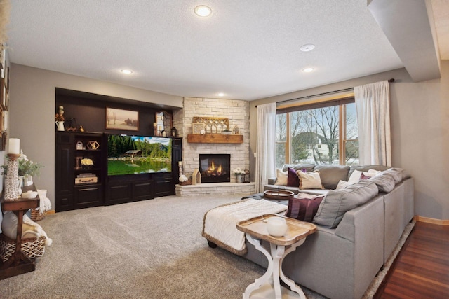 living room with a fireplace, a textured ceiling, and dark colored carpet