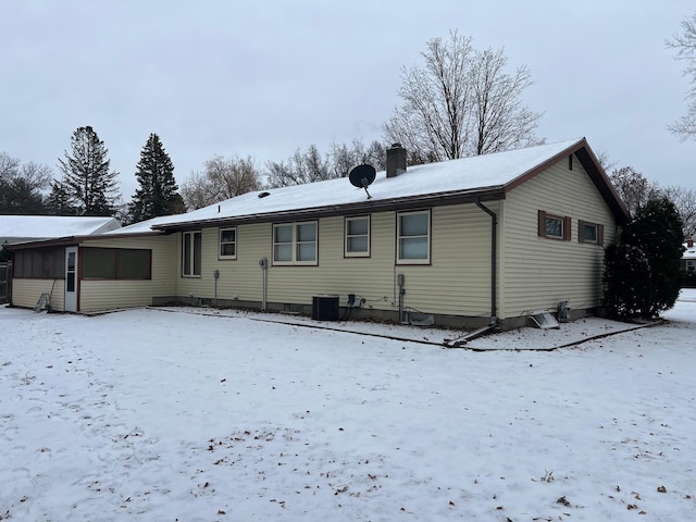 snow covered back of property featuring central AC