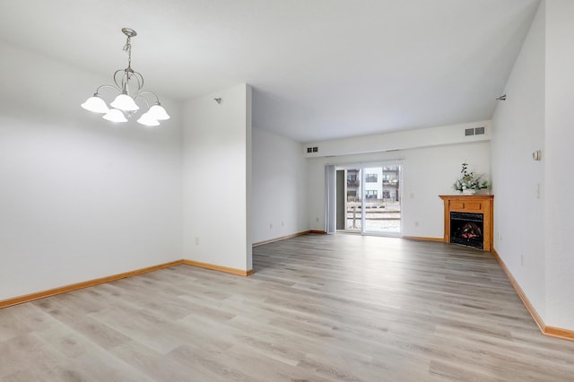 unfurnished living room with light hardwood / wood-style floors and a chandelier