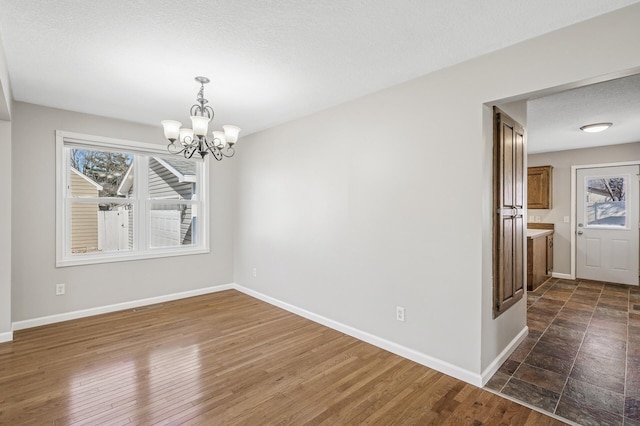 unfurnished dining area with baseboards, a healthy amount of sunlight, and an inviting chandelier