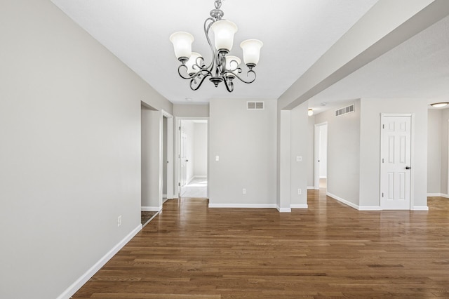 spare room featuring wood finished floors, visible vents, and a chandelier