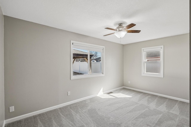 empty room with baseboards, light carpet, a textured ceiling, and ceiling fan