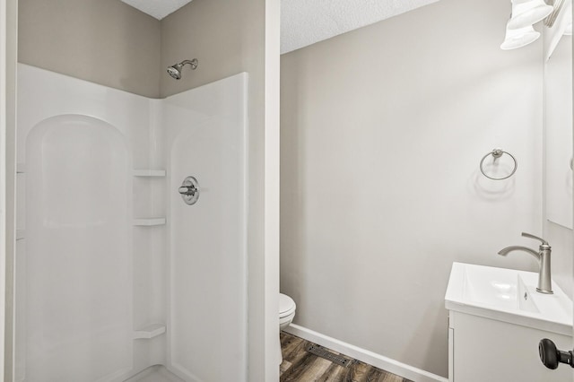 bathroom with vanity, wood finished floors, walk in shower, a textured ceiling, and toilet