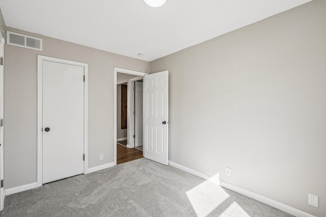 unfurnished bedroom with carpet, visible vents, and baseboards