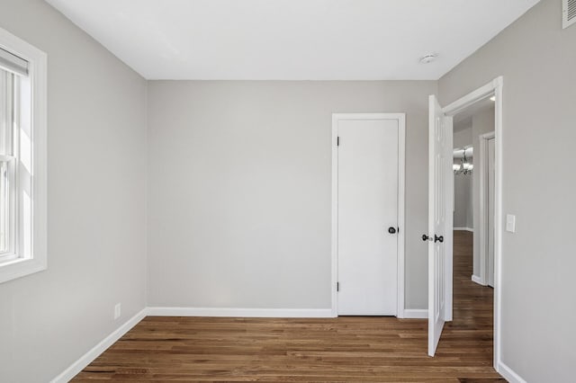 empty room featuring visible vents, wood finished floors, and baseboards