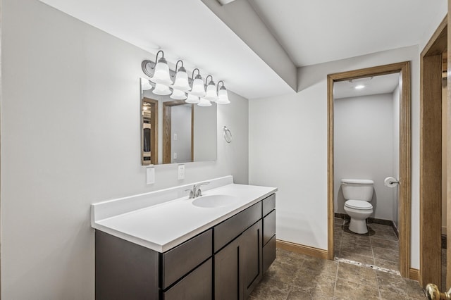 bathroom with toilet, vanity, and baseboards