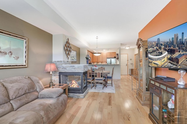 living room with light hardwood / wood-style floors and a stone fireplace